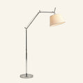 Polished aluminum swing arm floor lamp with tapered ivory fabric shade and round chrome base on cream studio background.