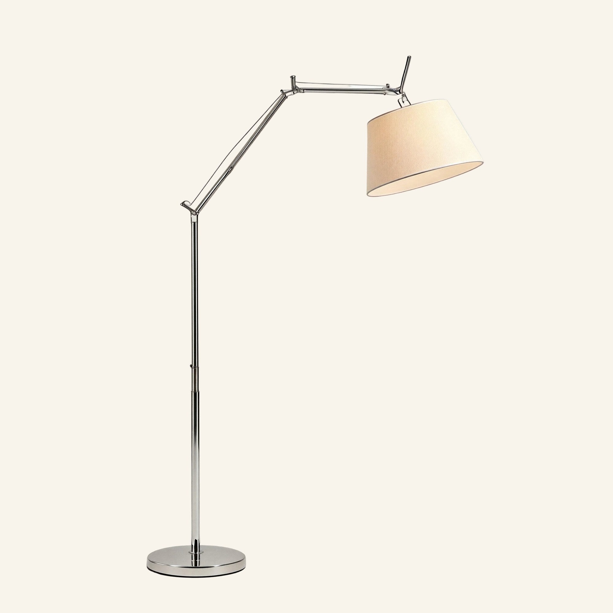 Polished aluminum swing arm floor lamp with tapered ivory fabric shade and round chrome base on cream studio background.