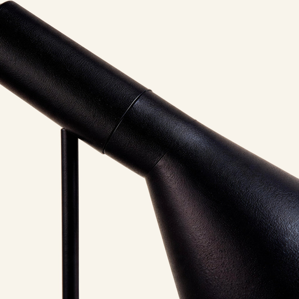 Close-up of the matte black enamelled metal shade and pivot joint, showing fine grain texture and the slim cylindrical arm of the task lamp