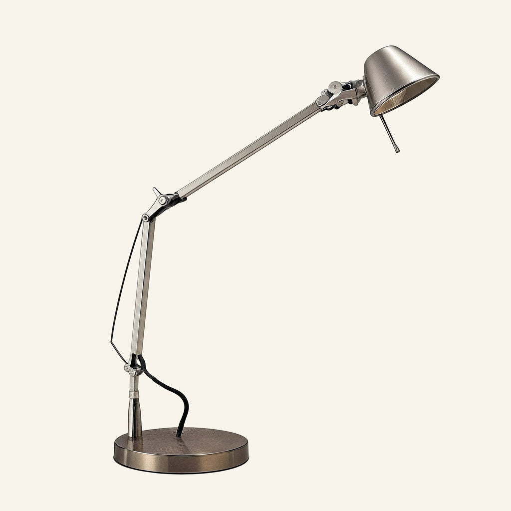 Silver aluminum swing arm desk lamp with conical shade, counterweight cable, and weighted disc base on cream backdrop