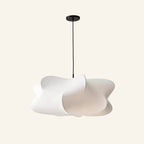Cloud-shaped white faux silk pendant lamp with irregular sculptural lobes, suspended from a black canopy on cream studio backdrop.