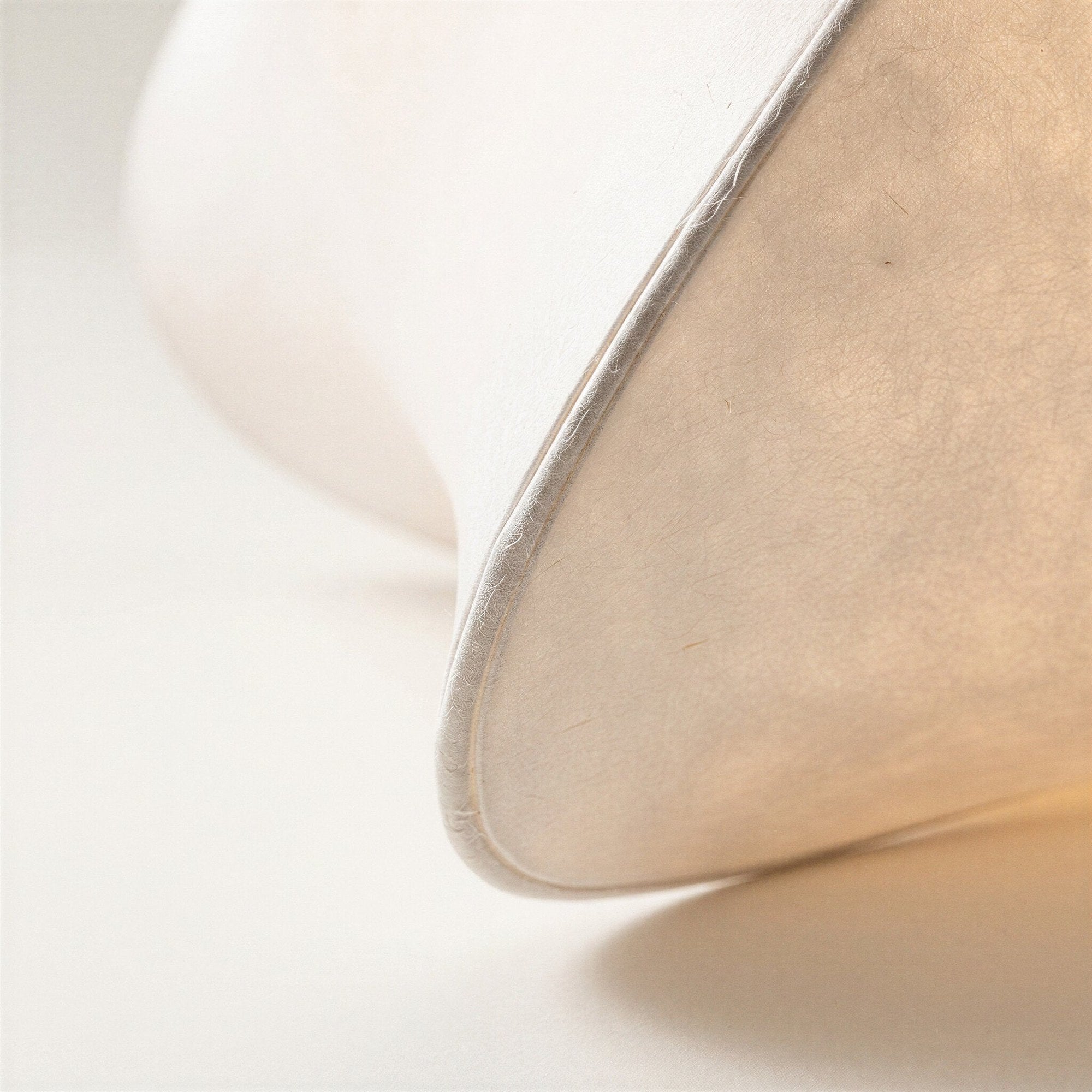 Close-up of softly curved faux silk shade showing fine fiber texture and stitched seam along the lobed edge.