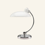 White lacquered version of the dome table lamp with curved chrome stem and circular base, photographed against a soft cream background.