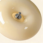 Close-up of the polished chrome finial seated against glossy cream-yellow opal glass, highlighting the smooth curvature and warm translucent shade.