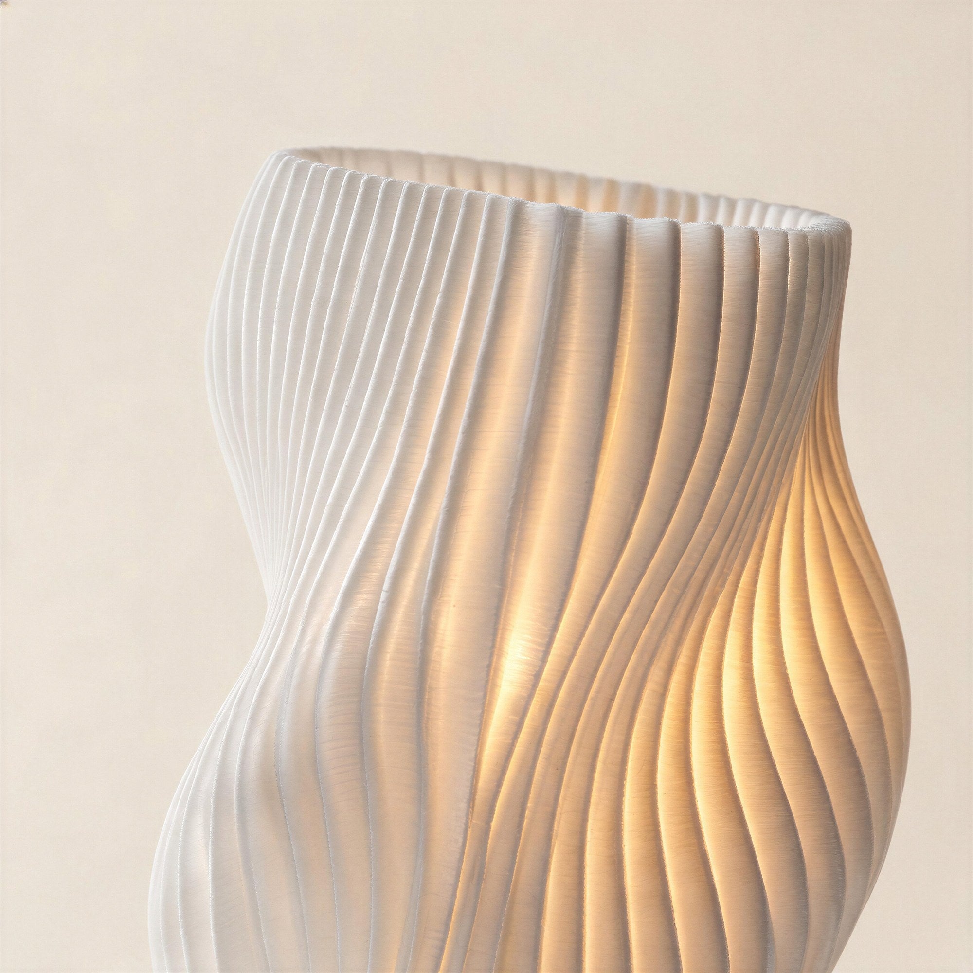 Close-up of the ribbed twisted shade glowing warmly from within, showing the fine printed line texture of the cordless LED lamp.