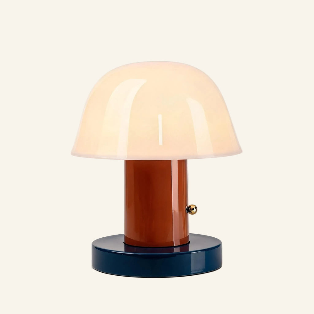 Alternate colorway with terracotta stem and dark navy base supporting the opal glass dome shade, brass touch button detail