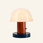 Alternate colorway with terracotta stem and dark navy base supporting the opal glass dome shade, brass touch button detail
