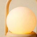 Close-up of the frosted glass globe diffuser resting on its round base, soft matte ABS handle arching behind in warm amber light.