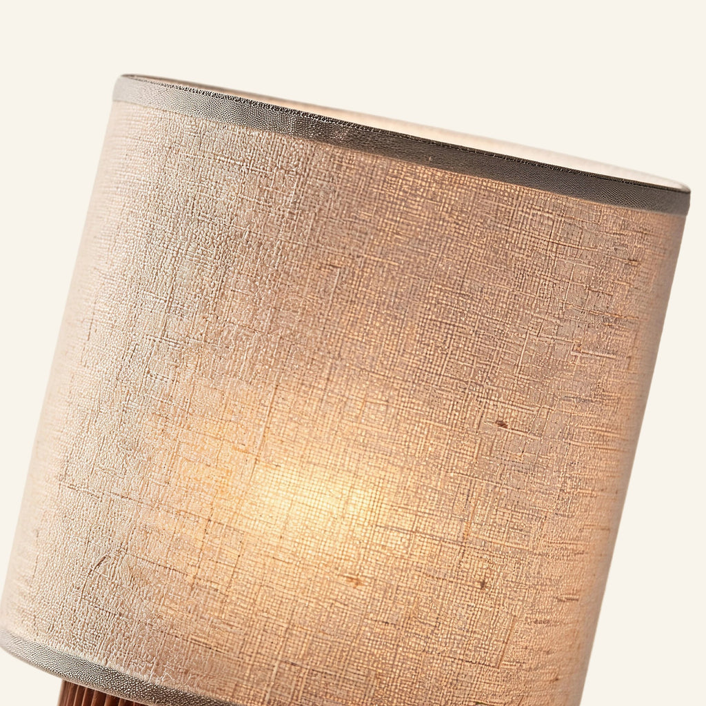 Close-up of woven linen shade revealing natural fiber texture, soft warm glow filtering through the cream cylindrical drum.
