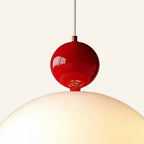Close-up of glossy red lacquered metal ball cap meeting the opal glass dome, showing reflections and warm bulb glow inside