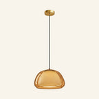 Amber-tinted variant of the dome pendant glowing softly, showing the rounded outer glass and inner diffuser on neutral background