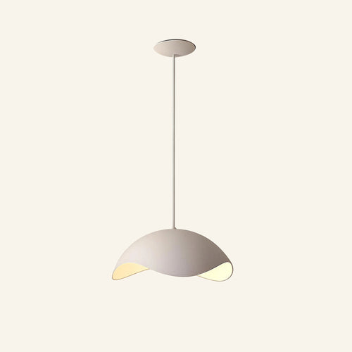 Asymmetric sand-white composite dome pendant on slim drop rod, scooped rim revealing warm LED glow underneath, shown on cream studio backdrop.