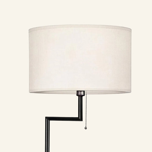 Close-up of the white linen drum shade and angled black steel arm with beaded pull-chain switch on the floor lamp.