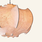 Close-up of draped faux-silk fabric showing creased linen-paper texture and visible iron ribs forming the cocoon pendant shade's petal structure