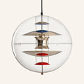 Clear glass globe pendant lamp on cream backdrop, polished metal hourglass diffuser stacked with blue and red reflector discs inside the sphere.