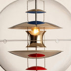 Close-up of stacked chrome reflector discs with blue and red undersides, lit bulb glowing within a polished metal core suspended on thin chains.