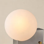 Close-up of the warmly lit opal glass orb showing soft inner glow and matte frosted surface above the chrome housing.