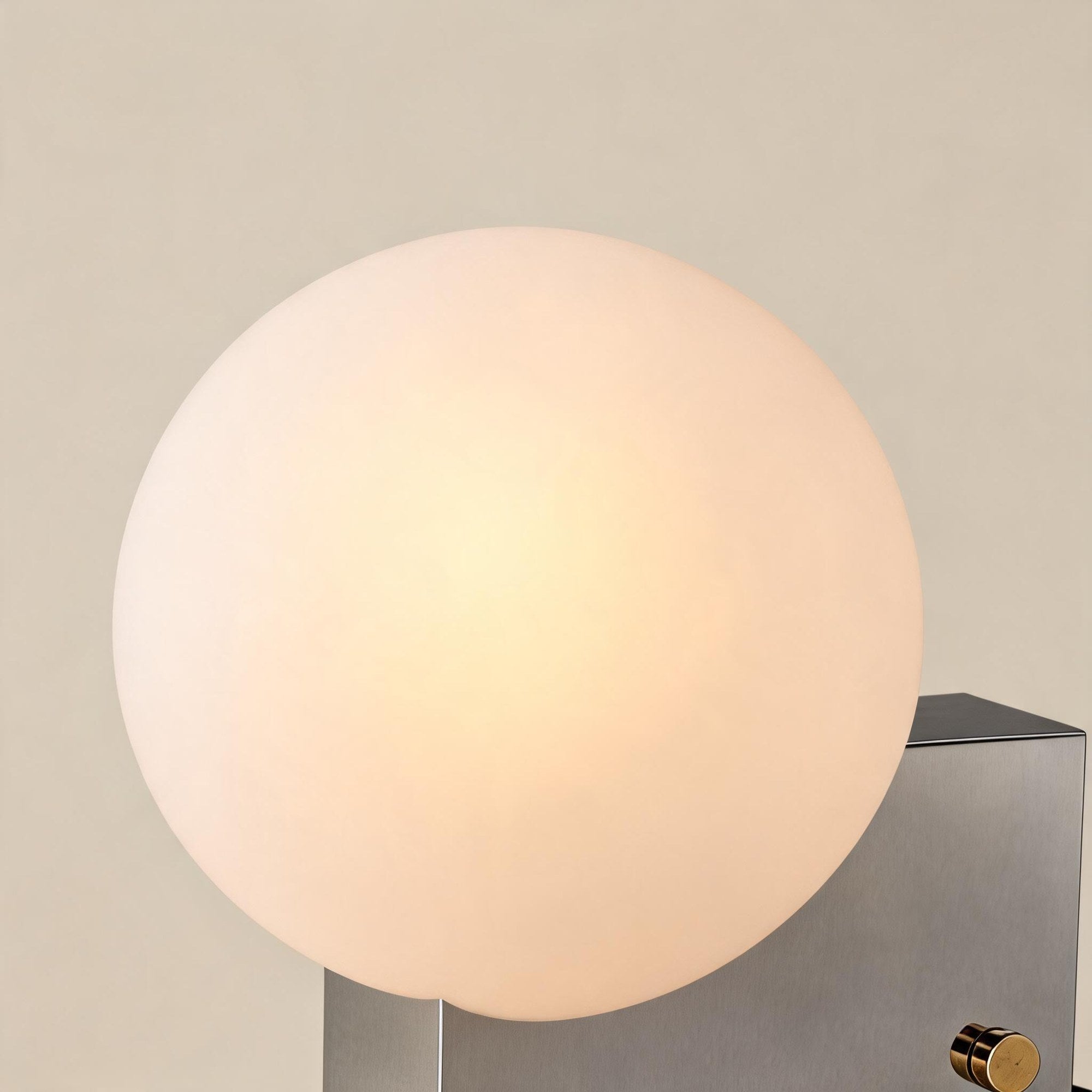 Close-up of the warmly lit opal glass orb showing soft inner glow and matte frosted surface above the chrome housing.