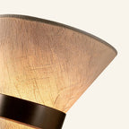 Close-up of crosshatched linen shade texture meeting the bronze iron cinch band, showing weave detail and warm tonal shift.