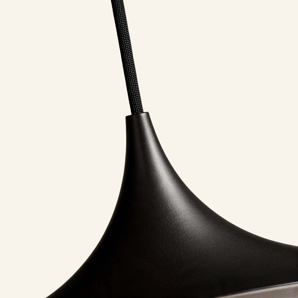 Close-up of the slender spun-metal neck flaring into the curved shade, showing fine matte black texture and braided fabric cord.