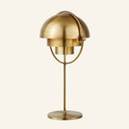 Alternate brass-shade version of the dual-dome table lamp, warm metallic finish across both hemispherical shades, ring, stem and round base.