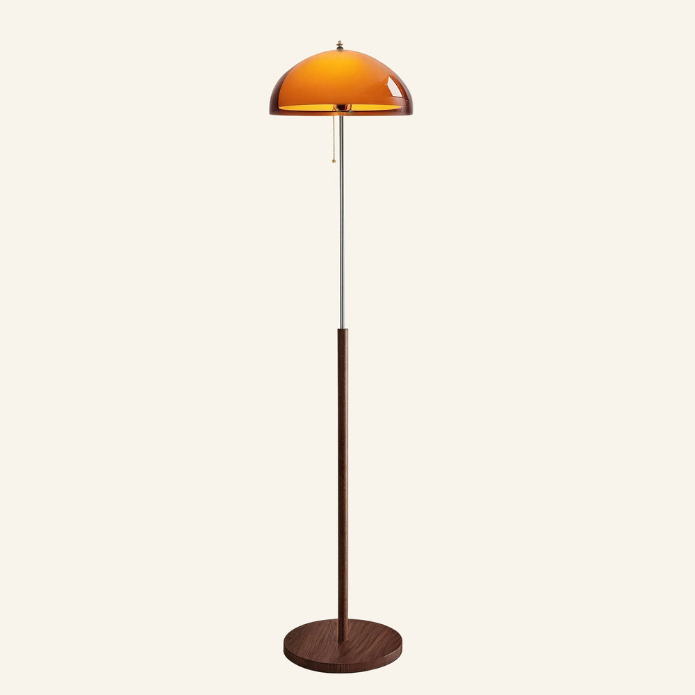 Domed amber acrylic shade glows above a slim chrome and walnut stem with brass pull-chain, mid-century floor lamp on round wooden base