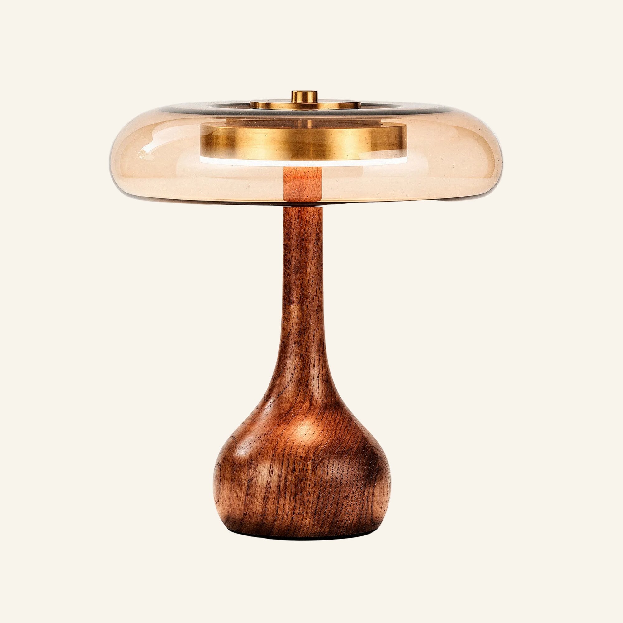 Side view of the mushroom-shaped lamp with bulbous turned-wood pedestal and translucent amber glass shade casting a soft warm halo