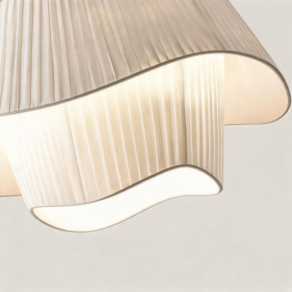 Close-up of finely pleated cream silk shade revealing the rippled wavy hem and warm glow from the inner E27 bulb