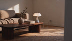 Cinematic video of a scalloped opal mushroom table lamp glowing on a wooden coffee table beside books and a stoneware vase.
