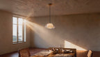 Cinematic video of a double glass dome pendant light glowing above a rustic dining table as golden sunlight streams through a window.