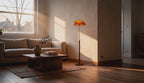 Cinematic video of an amber dome floor lamp glowing beside a linen sofa in a sunlit living room.