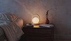 Cinematic video of a cordless LED globe lantern lamp glowing softly on a wooden bedside table in a dim bedroom.