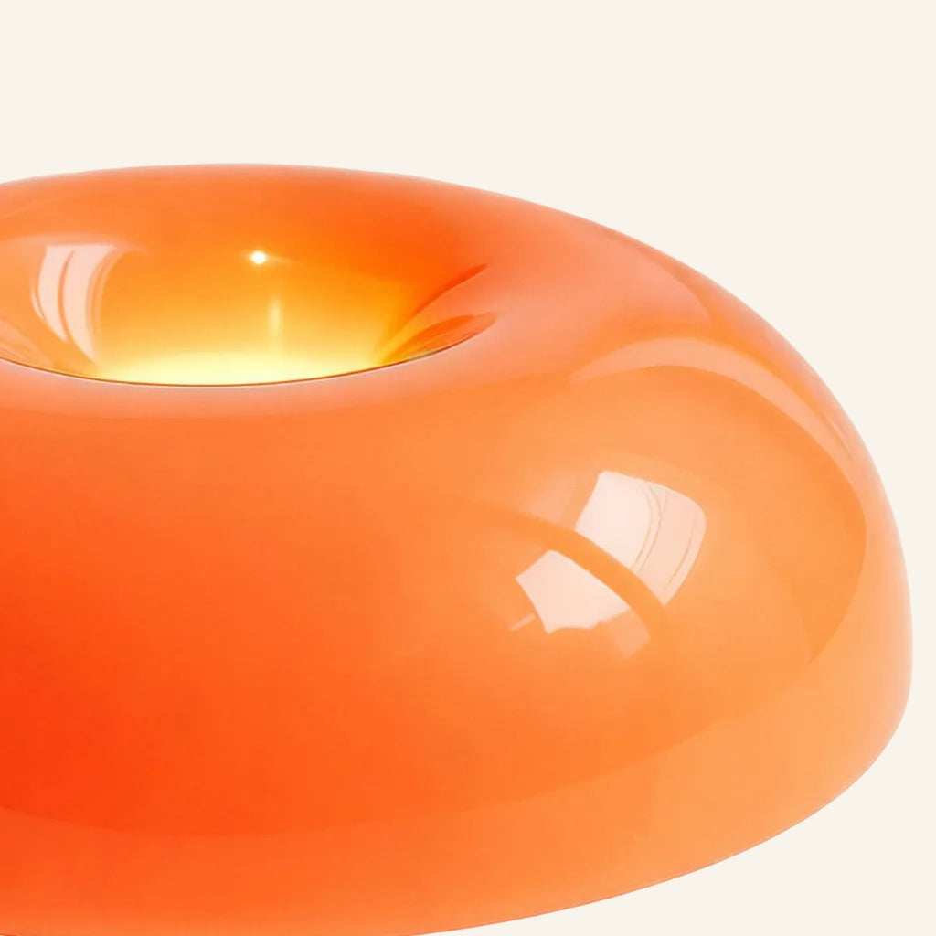 Close-up of the translucent orange acrylic dome showing its smooth high-gloss finish and warm glow pooling inside the central recess.