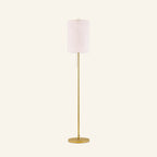Slim floor lamp with cream linen drum shade on a slender brass-finished steel pole, round base, and pull-chain switch shown on cream backdrop.