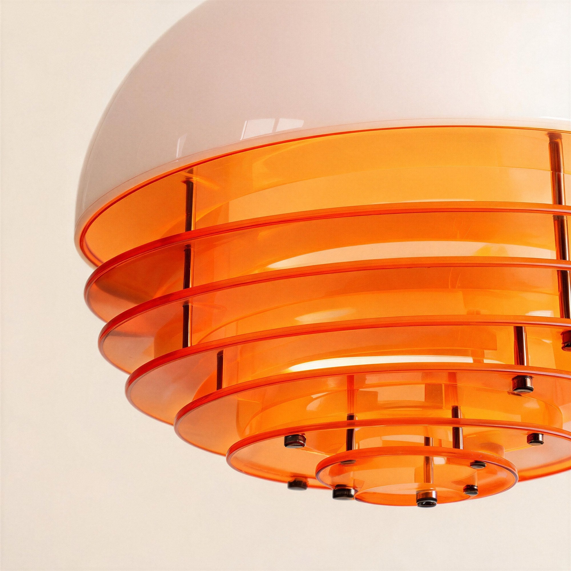 Close-up of the pendant's underside showing layered orange acrylic discs joined by small chrome bolts beneath the glossy white glass shade.
