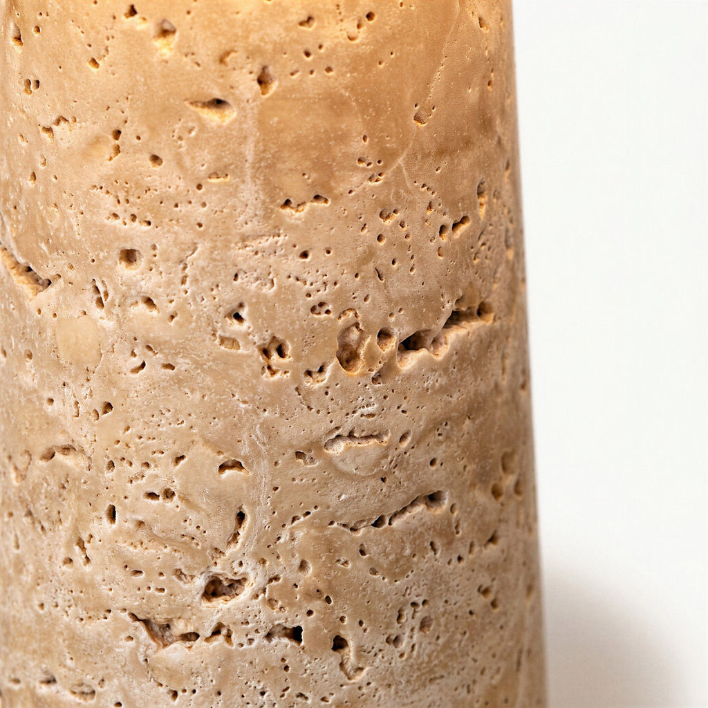 Close-up of the travertine base showing pitted natural cavities, warm beige veining, and the porous stone texture of the lamp column