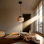 Travertine pendant lamp hanging over a wooden dining table at sunset with wine glasses and a bowl of figs.