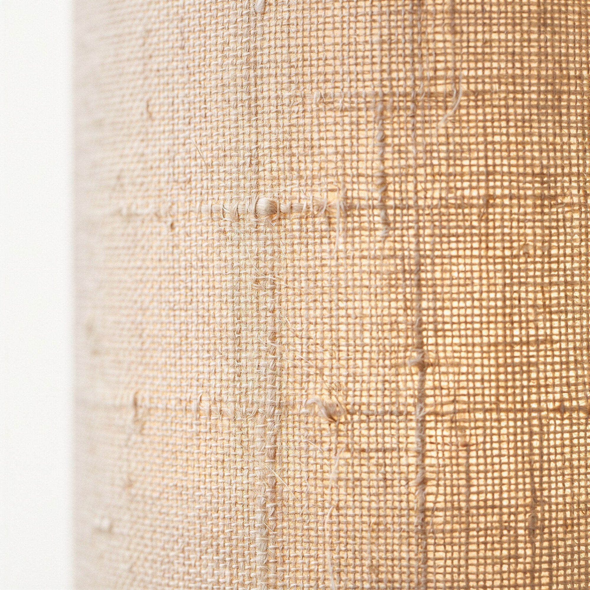 Close-up of the natural beige linen fabric shade revealing its open weave and visible woven seams.