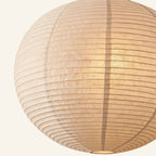 Close-up of the ribbed rice paper globe shade showing soft seams, fibrous texture, and warm internal glow.